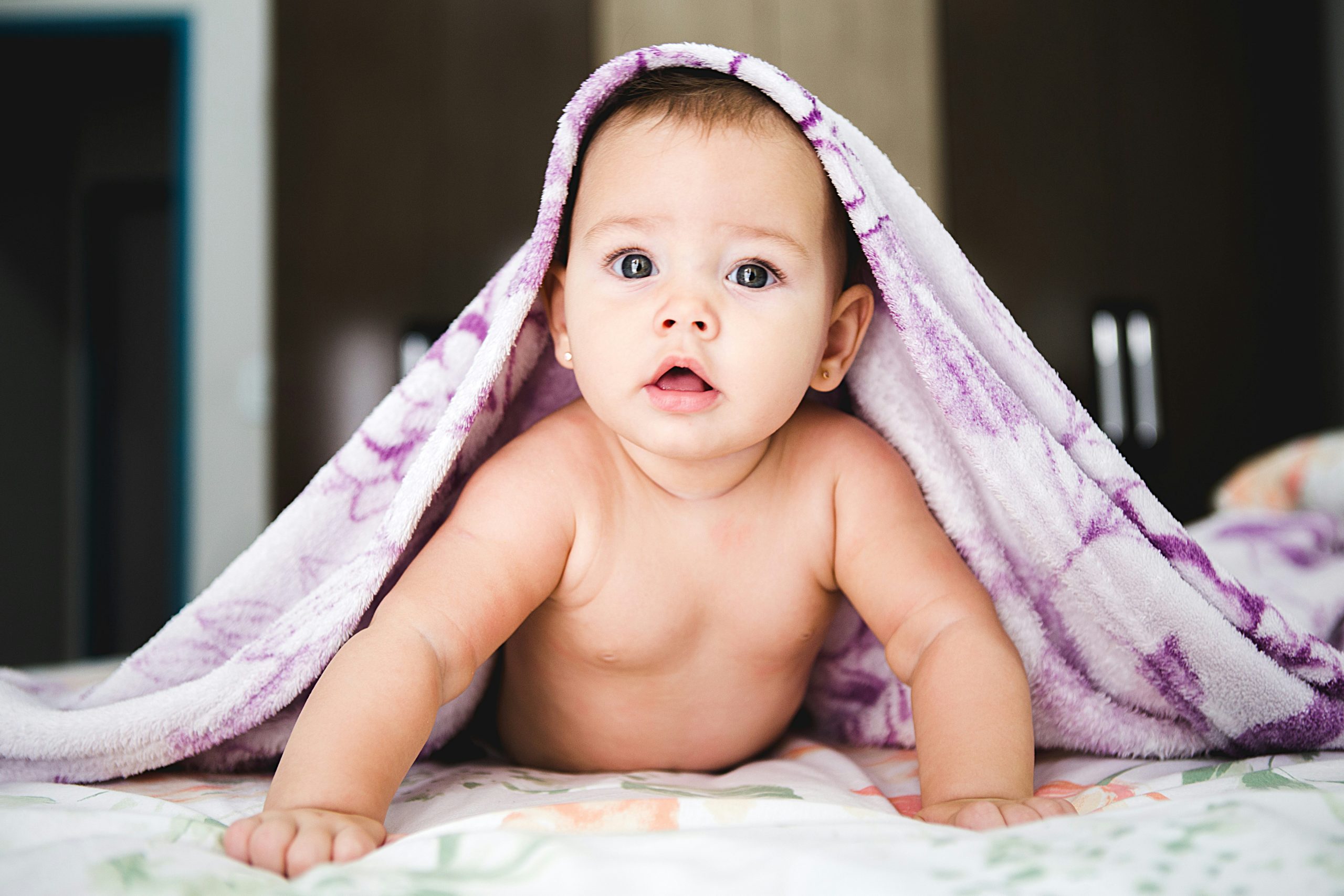 Baby peeking out from under purple blanket